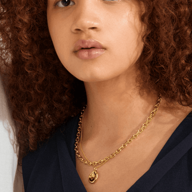 Woman wearing a gold necklace with a pendant