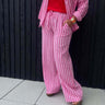 Person wearing a pink and white striped outfit with a red top against a black background