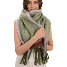 Woman wearing a green and purple scarf with fringe on a white background