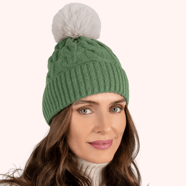 Green knit beanie with a white pom-pom worn by a model on a white background