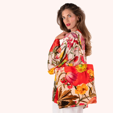 Woman wearing a colorful floral top and white pants on a white background