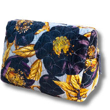 A quilted cosmetic pouch featuring a floral pattern with dark navy, purple, and yellow flowers on a light gray background, shown on a white background with a soft drop shadow.