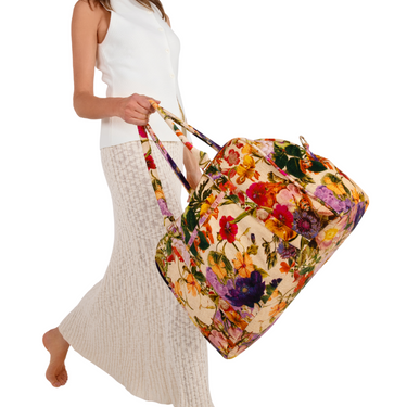 Woman holding a large floral-patterned bag on a white background