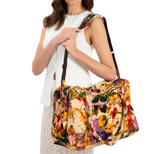 Woman holding a colorful floral-patterned handbag against a white background