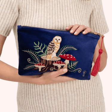 Navy blue pouch with owl and mushroom design held by a person wearing a beige sweater.