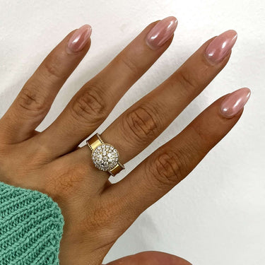 Hand wearing a diamond ring with a green sweater on a white background