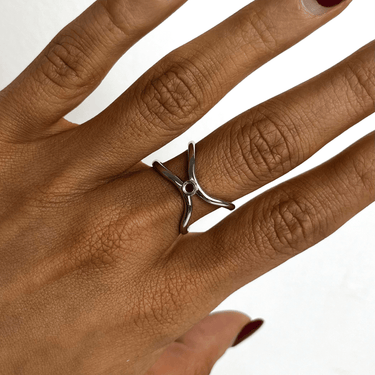 Hand wearing a silver ring with a unique design on a white background