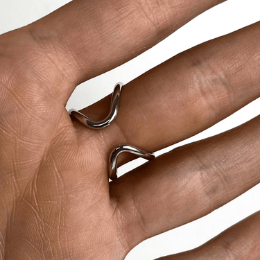 Silver ring on a person's finger with a plain background