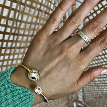 Hand wearing gold rings with a textured background