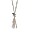 A gold-toned lariat-style necklace with a tassel pendant, featuring a black rectangular stone and a small amber-colored bead accent, shown against a plain white background.