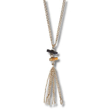 A gold-toned lariat-style necklace with a tassel pendant, featuring a black rectangular stone and a small amber-colored bead accent, shown against a plain white background.