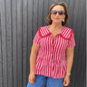 Woman wearing a red and white striped shirt against a gray wooden background