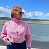 Woman in a pink shirt standing on an airport observation deck with a scenic view.