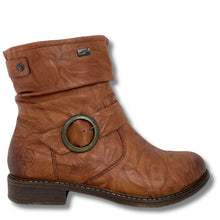 A brown leather ankle boot with a rolled cuff, a large round metal buckle detail on the side, and a low stacked heel, shown against a plain white background.