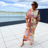 Woman wearing a colorful patterned dress standing on a rooftop with a scenic view.