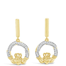 A pair of gold dangle earrings with a circular design paved with clear stones and a small gold crown at the bottom, shown on a plain white background.