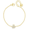 A delicate yellow gold chain bracelet with a small four-leaf clover charm paved with clear stones, displayed on a clean white background. The bracelet features a lobster clasp, an extender chain, and a round engraved tag.