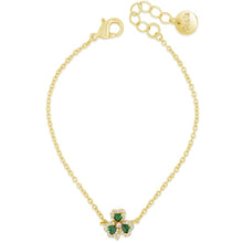 A delicate gold chain bracelet featuring a shamrock charm with green emerald-cut stones and clear crystal accents, displayed on a clean white background.