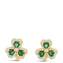 A pair of gold shamrock stud earrings with green heart-shaped emerald-cut stones and small clear accent stones, shown on a plain white background.