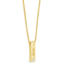 A gold bar pendant necklace with a small clear gemstone and the word 'One' engraved on the front, suspended from a gold chain against a white background.