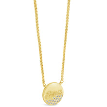A gold chain necklace with a round gold pendant engraved with the brand name 'Swarovski' and accented with small clear crystals, shown on a plain white background.