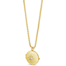 A gold locket necklace featuring a round, hinged gold pendant with a starburst design and a small clear gemstone in the center, suspended from a gold chain on a white background.