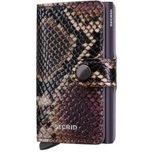 A Secrid Miniwallet in a snakeskin pattern featuring shades of brown, black, and purple, with a dark metallic snap button and side clip, shown on a plain white background.