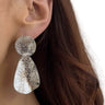 Silver earrings worn by a person with brown hair.