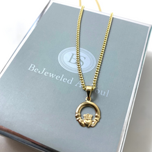 Gold necklace with a claddagh pendant on a branded box