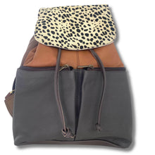 A multi-material backpack made of dark gray pebbled leather, brown leather, and a beige leopard print flap, shown on a white background.