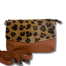 Leopard print crossbody bag with brown leather strap on a white background