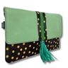 Green clutch with black and gold polka dot design on a white background