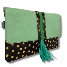 Green clutch with black and gold polka dot design on a white background