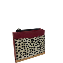 A small zippered card holder or wallet featuring a dalmatian print hair-on-hide front panel, a burgundy leather top section, and tan leather trim, shown on a plain white background.