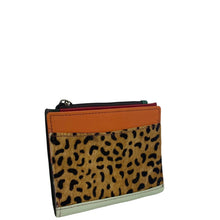 A small zippered card holder or wallet featuring a leopard print hair-on-hide front panel, a solid orange leather top band, and a light sage green base trim, shown on a plain white background.
