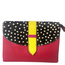 Polka dot clutch bag with pink base and yellow strap on a white background