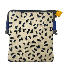Small pouch with black abstract pattern on beige fabric, blue straps, and yellow tag.