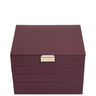 A rectangular leather jewelry box in deep burgundy with a textured finish and a small gold-tone metal plaque on the front, photographed against a solid white background.