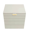 A light beige jewelry box with five drawers and a small gold-tone brand plaque on the front, set against a plain white background.