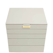 A light beige jewelry box with five drawers and a small gold-tone brand plaque on the front, set against a plain white background.