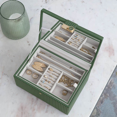 Green jewelry box with jewelry on a marble surface