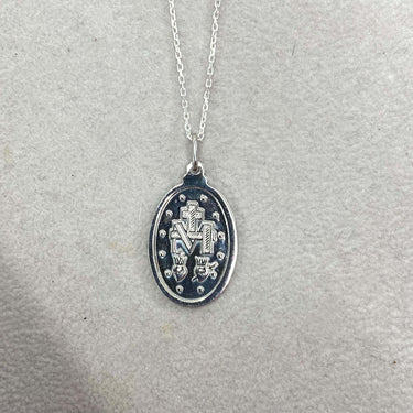 Silver necklace with an oval pendant on a light gray background