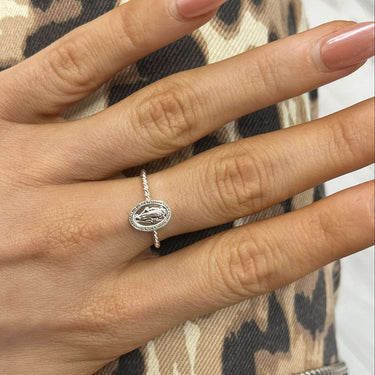 Hand wearing a ring with a leopard print sleeve in the background