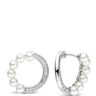 A pair of silver hoop earrings adorned with white freshwater pearls and a curved row of small clear pavé stones, shown against a plain white background.