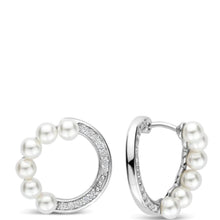 A pair of silver hoop earrings adorned with white freshwater pearls and a curved row of small clear pavé stones, shown against a plain white background.