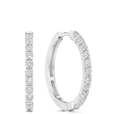 A pair of silver hoop earrings with a single row of round-cut clear gemstones along the front, shown on a plain white background.