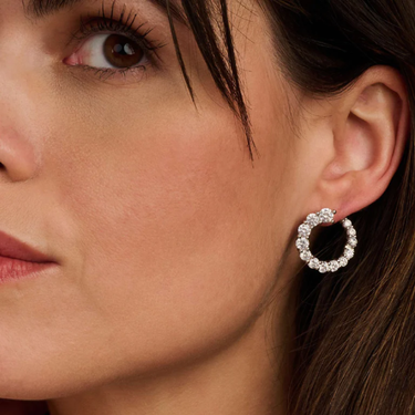 Close-up of a woman wearing a silver hoop earring with clear stones.