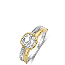A two-tone yellow gold and silver ring featuring a cushion-cut clear center stone and a pavé-set silver band with a yellow gold accent.
