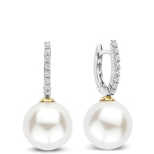 A pair of drop earrings featuring large white freshwater pearls suspended from silver huggie hoops adorned with pavé-set clear cubic zirconia and gold accents.