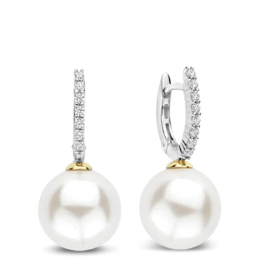 A pair of drop earrings featuring large white freshwater pearls suspended from silver huggie hoops adorned with pavé-set clear cubic zirconia and gold accents.